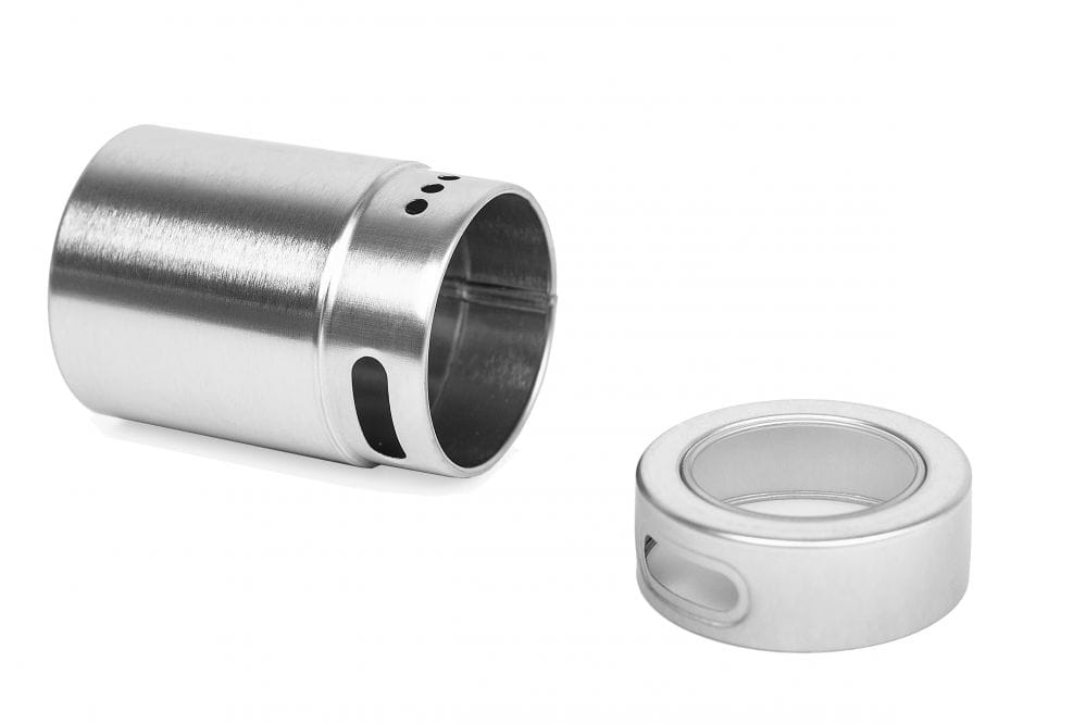 Saupoudreur à épices rond ouvert en métal couleur argent, composé d'un insert verseur perforé et d'un couvercle à fenêtre de visualisation retiré, photographié sur fond blanc.