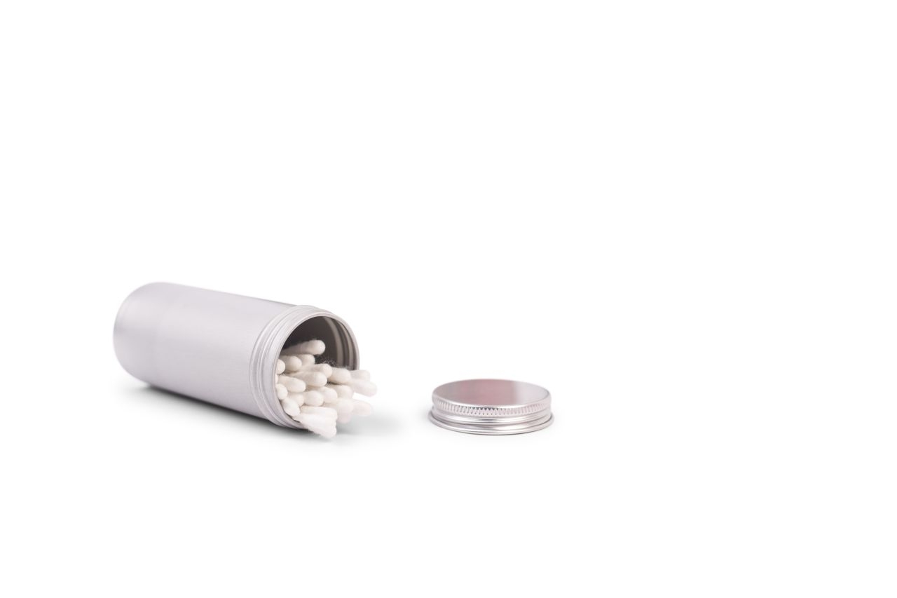 Boîte en aluminium ouverte de 135 ml, remplie de bâtonnets de coton, à côté du couvercle dévissé.