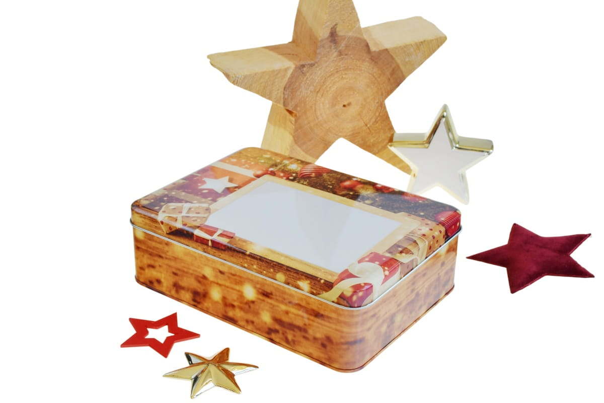 Boîte métallique de Noël fermée en finition bois, décorée d'étoiles et d'éléments festifs, sur fond blanc.