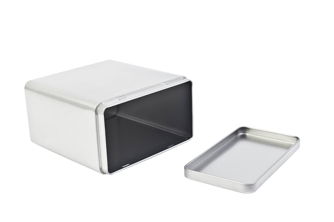 Boîte métallique carrée ouverte avec couvercle à pince amovible, couleur argent, photographiée sur fond blanc.