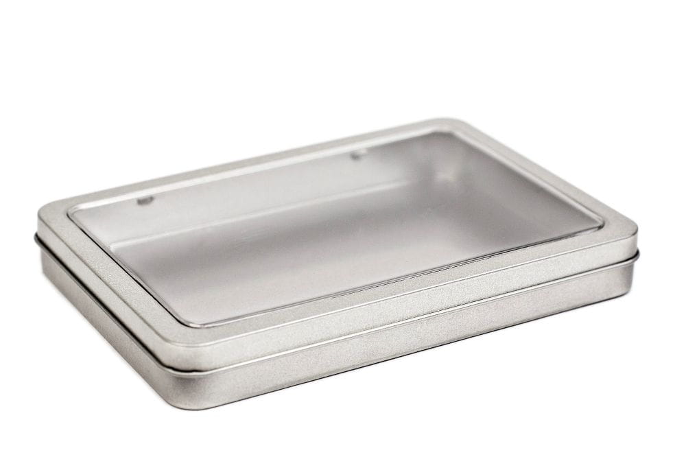 Boîte DIN-A6 fermée, plate, en fer blanc de couleur argentée avec couvercle amovible et fenêtre de visualisation transparente, photographiée sur fond blanc.