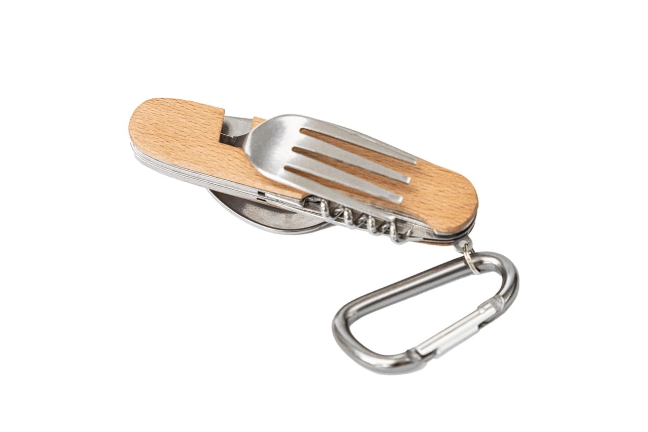 Couverts multifonctionnels repliés avec poignée en bois de hêtre clair, fourchette visible à l'extérieur, mousqueton argenté attaché, photographié sur fond blanc.