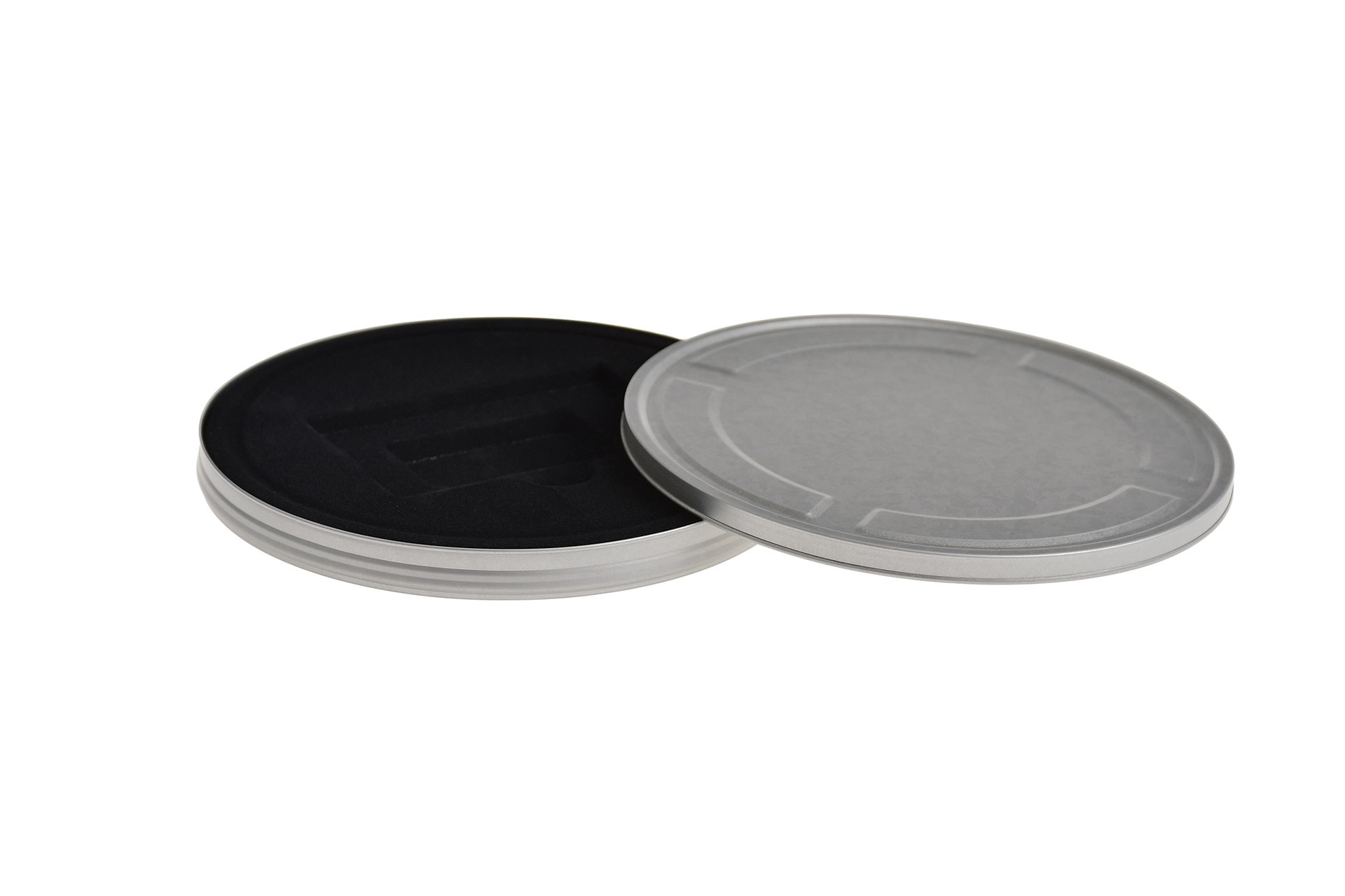 Boîte métallique ronde ouverte en métal couleur argent avec couvercle emboîtant retiré, doublure noire à l'intérieur pour ranger les bons de cinéma, photographiée sur fond blanc.