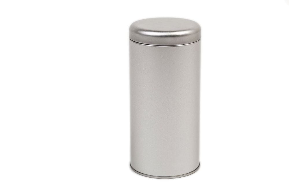 Boîte à thé ronde fermée en métal couleur argent avec couvercle emboîtant, photographiée sur fond blanc neutre.