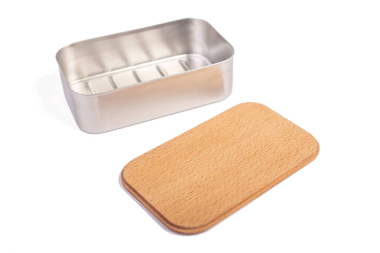 Boîte à lunch rectangulaire ouverte en acier inoxydable avec couvercle en bois de hêtre retiré, présentée sur fond blanc.