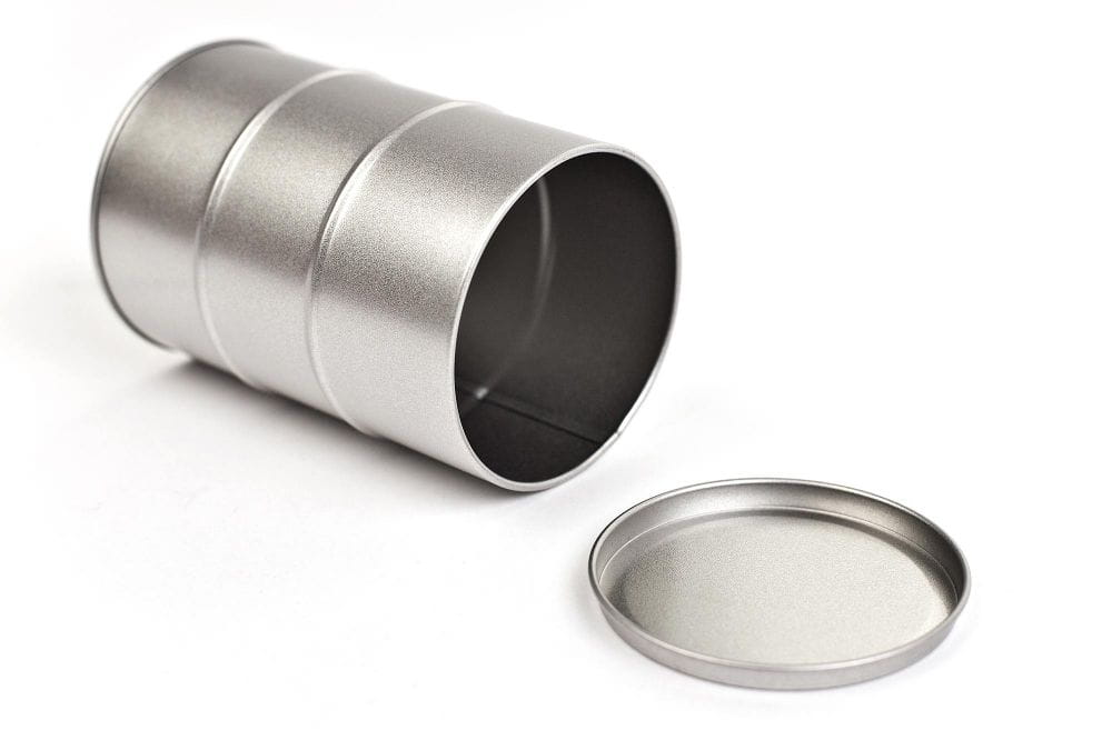 Boîte métallique ronde en forme de fût de pétrole ouverte, couleur argent, en position horizontale avec couvercle emboîtant retiré, photographiée sur fond blanc.
