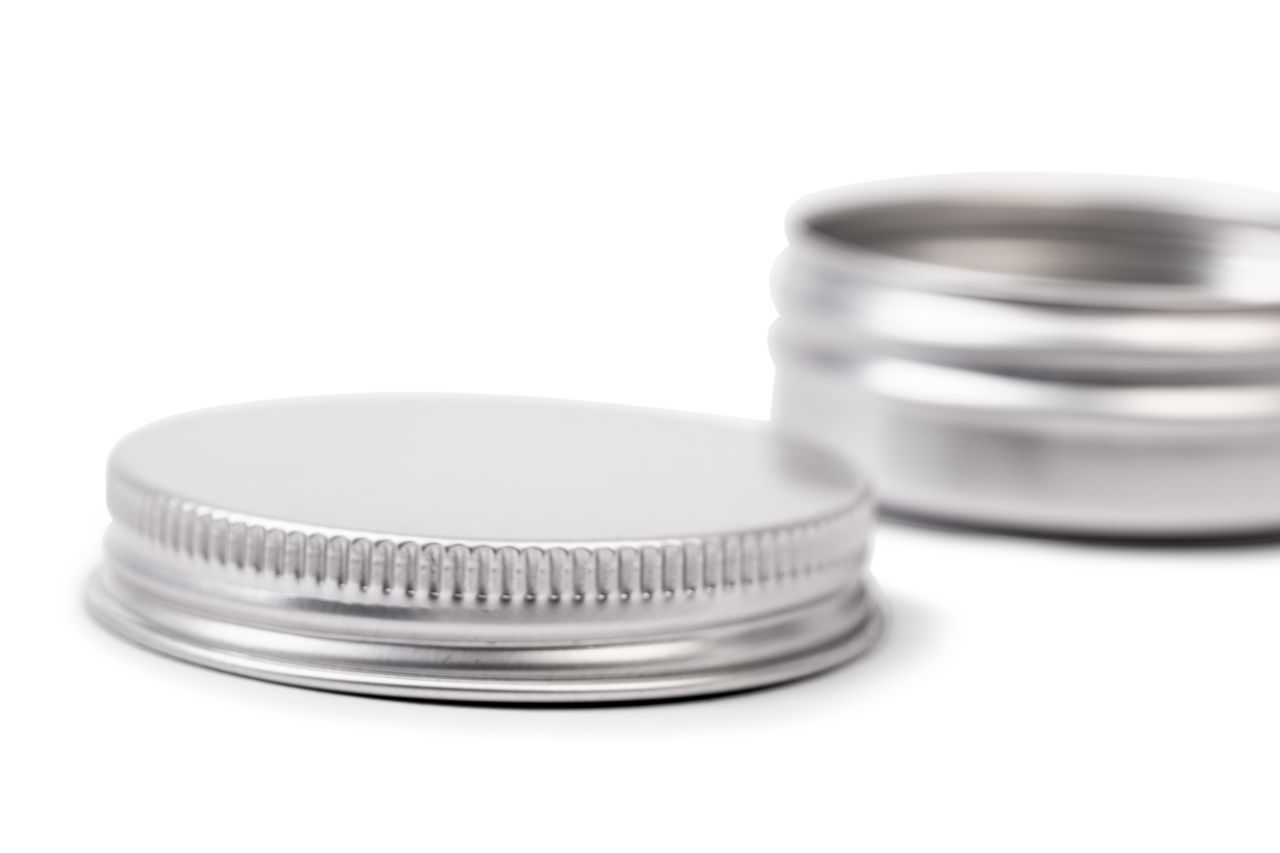 Gros plan détaillé d'un couvercle en aluminium plat avec fine rainure, la boîte ouverte légèrement floue en arrière-plan.