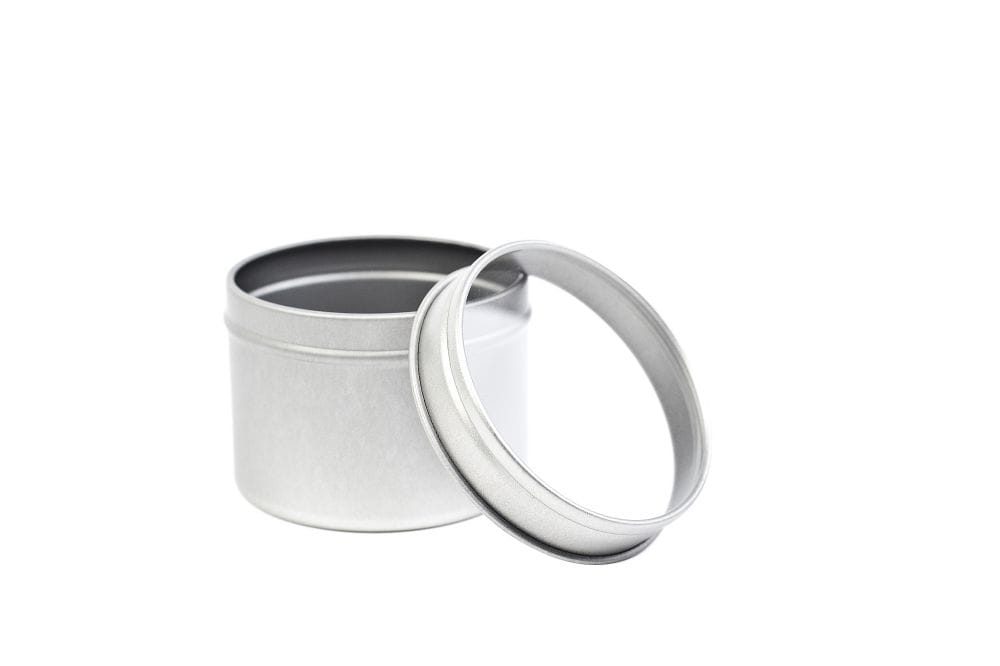 Boîte métallique ronde ouverte en métal couleur argent avec couvercle retiré et fenêtre transparente, fond neutre.