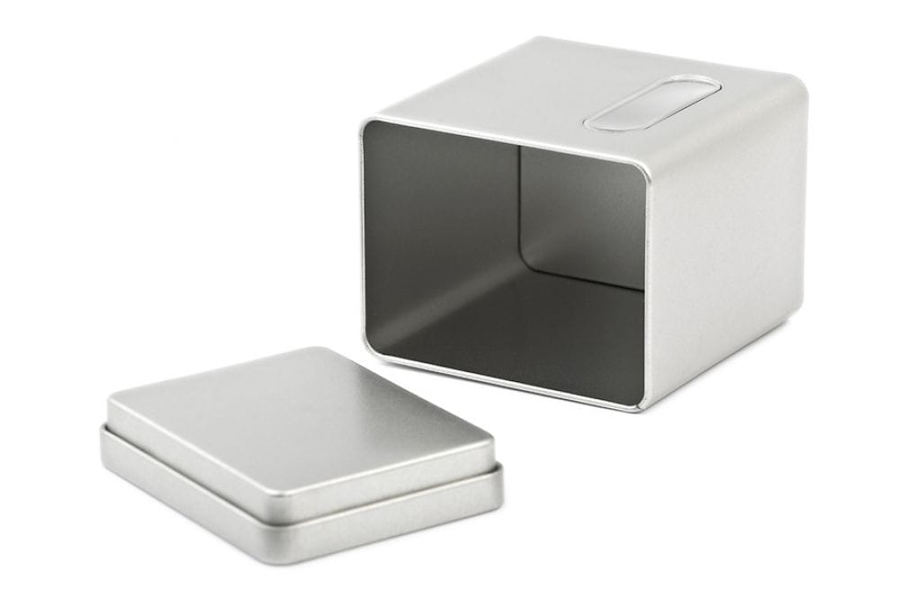Boîte de rangement ouverte en fer blanc, de couleur argentée, avec couvercle retiré, photographiée sur fond blanc.