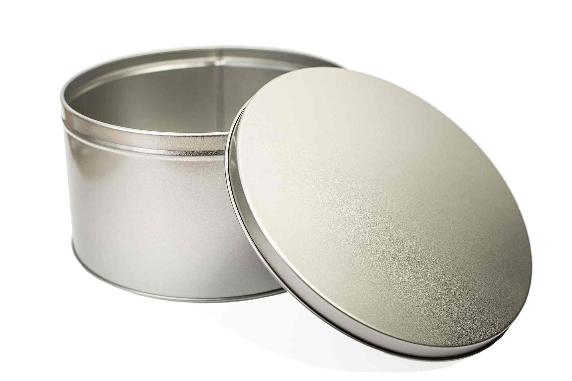 Boîte cadeau ronde ouverte en métal couleur argent avec couvercle amovible, debout sur fond blanc.