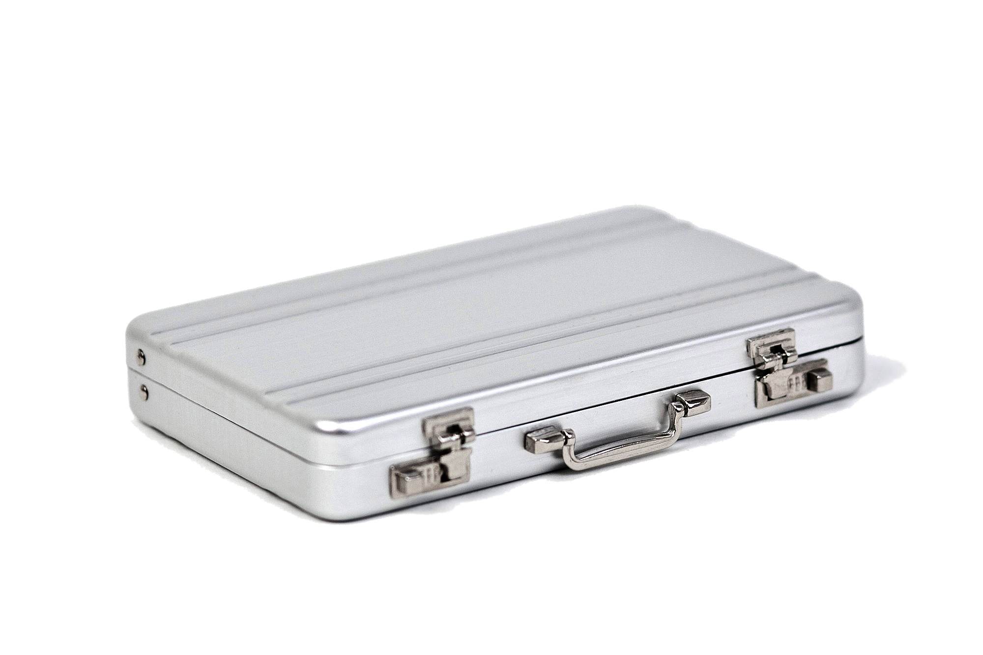Mini-mallette en aluminium rectangulaire fermée en argent avec fermetures métalliques et poignée de transport, sur fond blanc.