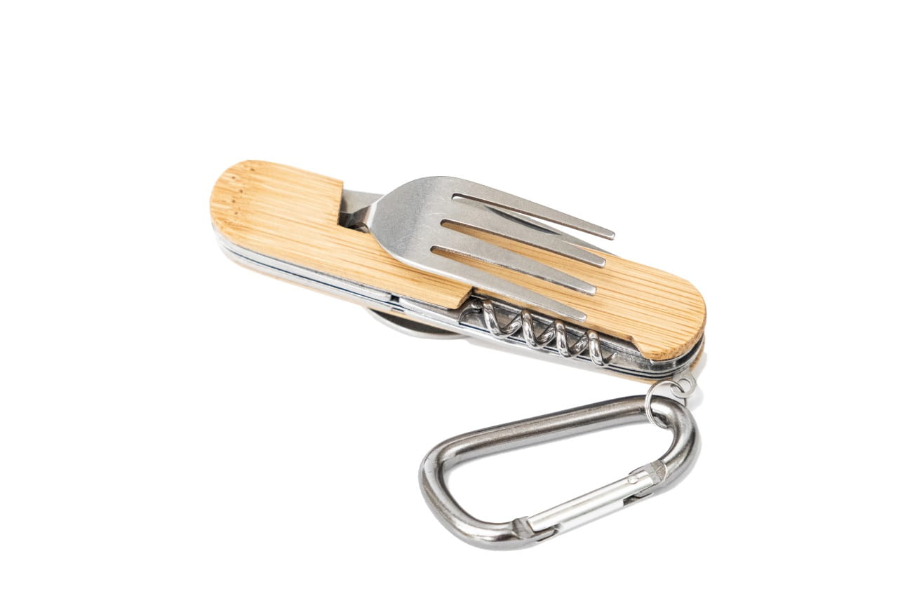 Couverts de camping multifonctionnels avec manche en bois de bambou clair, fermés. Visibles les dents de la fourchette et le tire-bouchon ; avec mousqueton couleur argentée, fond neutre.