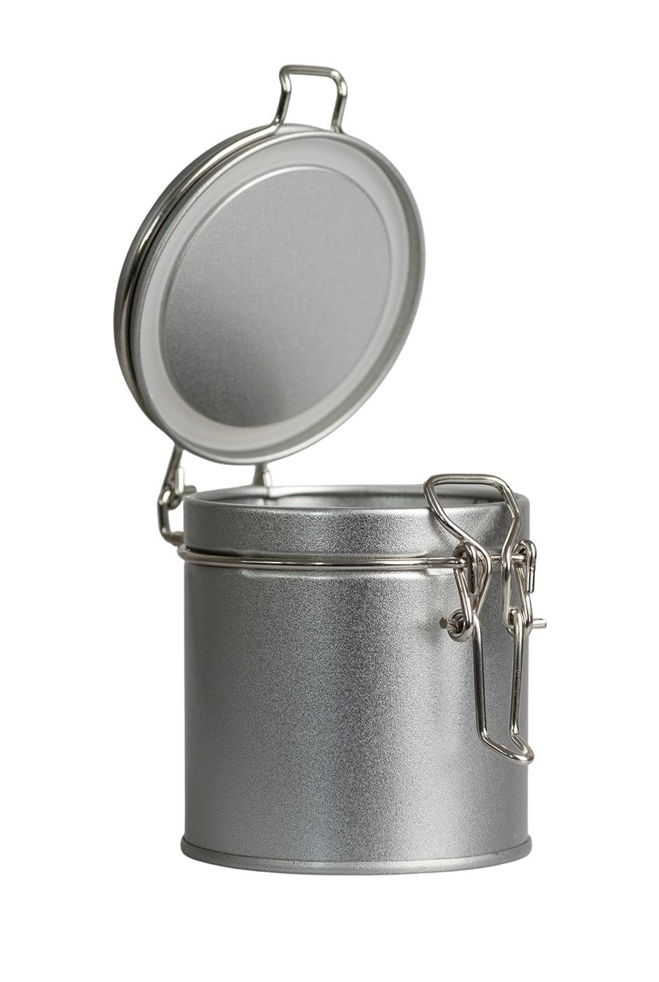 Petite boîte de rangement ronde ouverte en métal couleur argent avec couvercle à charnière relevé, debout sur fond blanc.