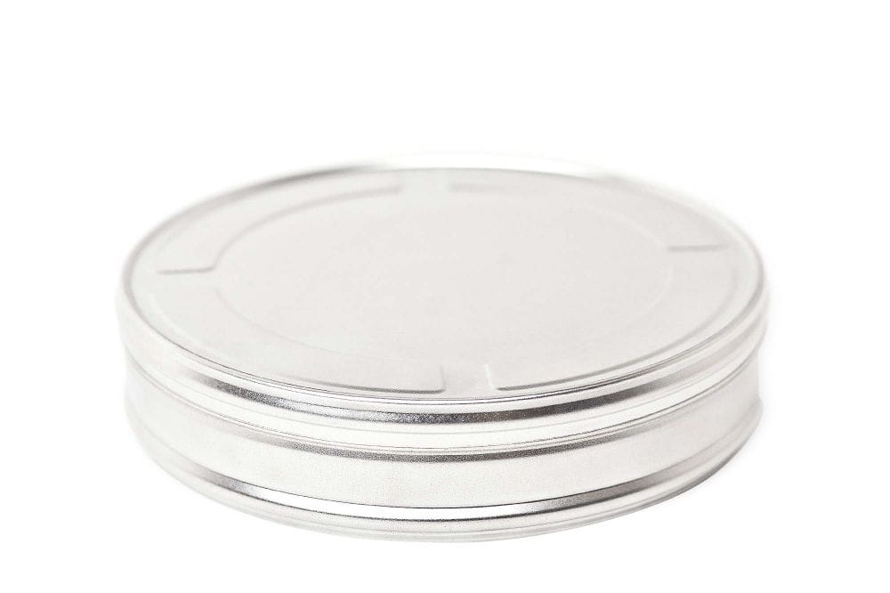 Boîte de film ronde fermée en métal argenté avec couvercle rapporté, fond blanc neutre.