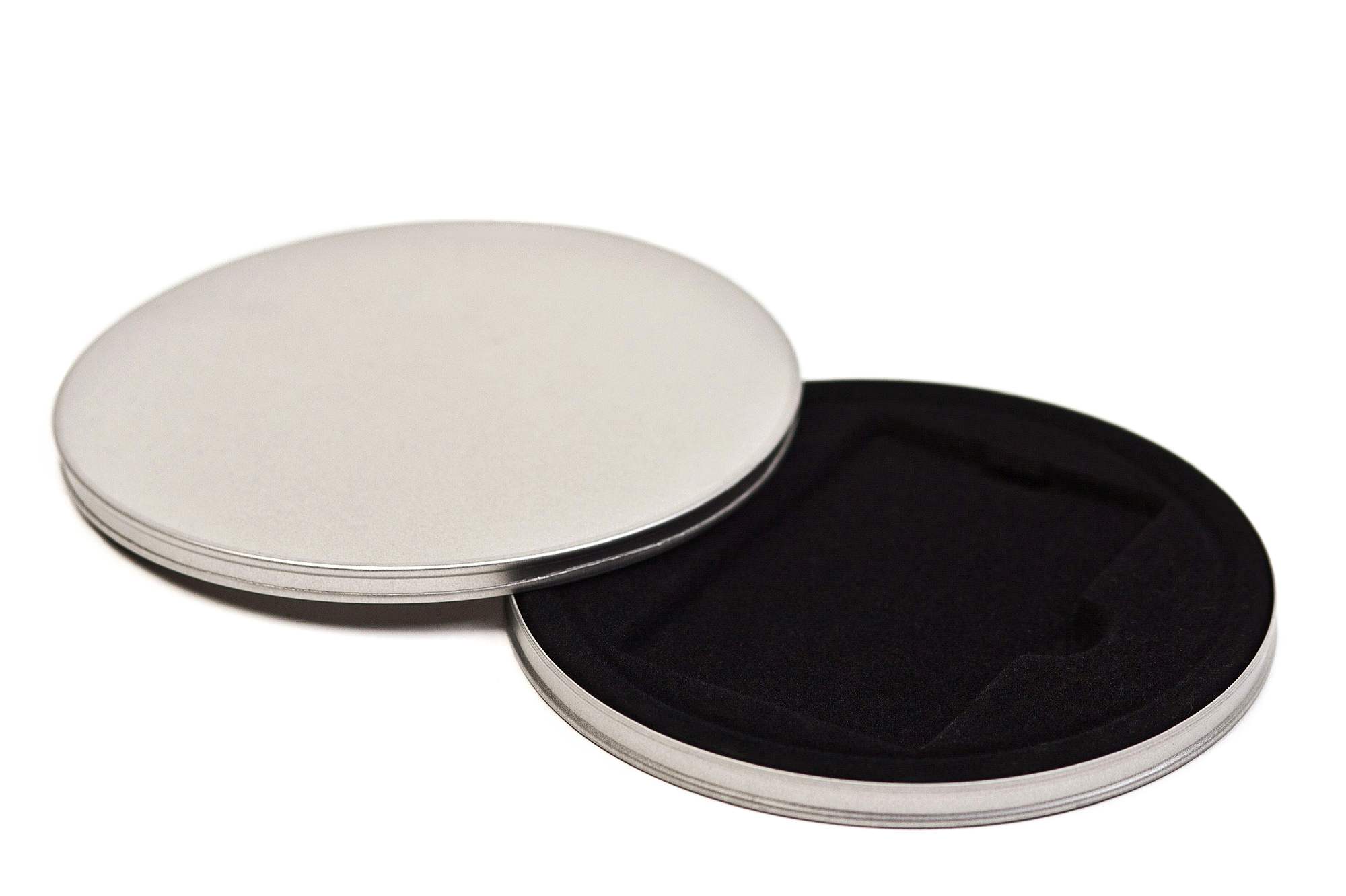 Boîte à bon d'achat ronde ouverte en métal couleur argent avec insert en velours noir, couvercle placé à côté, sur fond blanc.