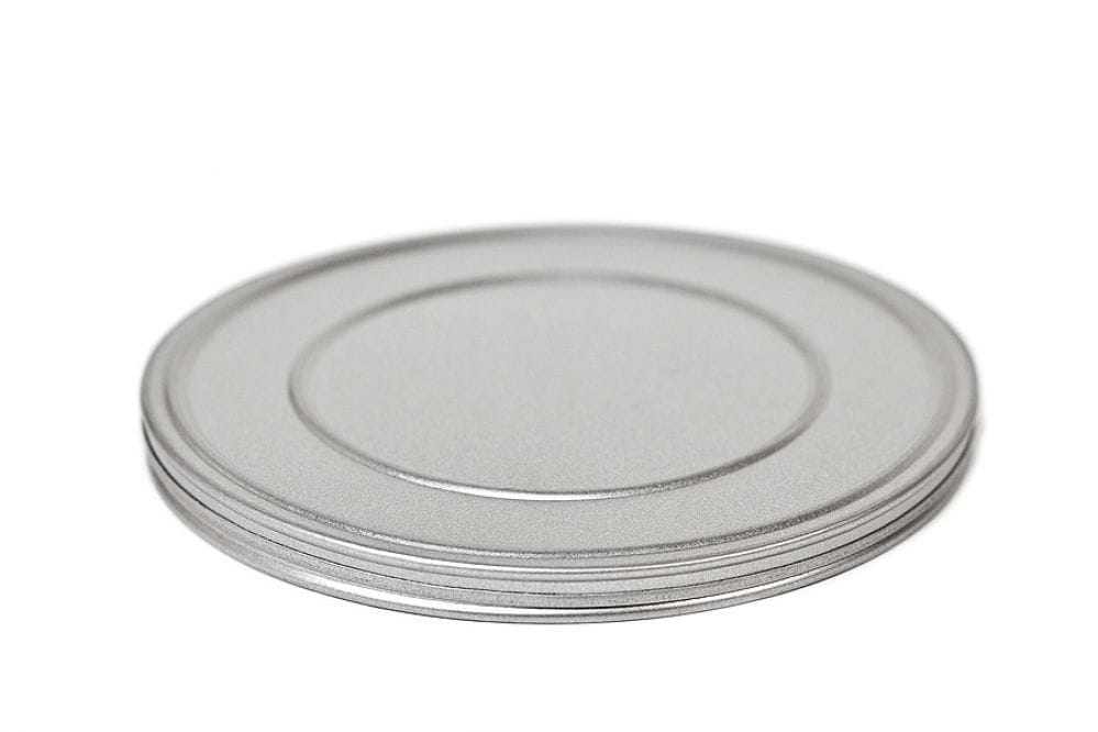 Boîte métallique ronde fermée en fer blanc argenté avec couvercle emboîtant plat, photographiée sur fond blanc.