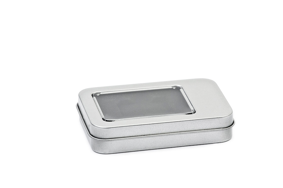 Boîte métallique rectangulaire fermée en métal argenté avec fenêtre transparente sur le couvercle, sur fond blanc.